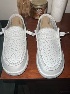 a pair of white shoes sitting on top of a wooden table