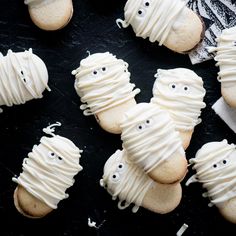 there are many cookies with icing on the black table and one cookie has eyes