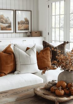 a living room filled with white couches and pillows on top of a wooden table