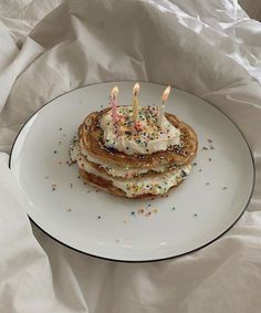 a stack of pancakes with white frosting and sprinkles on a plate