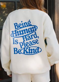 This Mayfair crewneck is a must have! It features "mayfair" embroidered on the middle chest and a graphic on the back stating, "Being Human Is Hard, Please Be Kind".  "At Mayfair, we do not confine ourselves to the standard in which society holds us to. We believe that it’s important to express yourself in a way that m Sweatshirt And Shirt Outfit, Church Merch, Res Life, Merch Ideas, Being Human, Young T, Trending Today, Graphic Crewneck Sweatshirt, Apparel Design