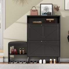 a black cabinet sitting in front of a wall with pictures on it and shoes next to it