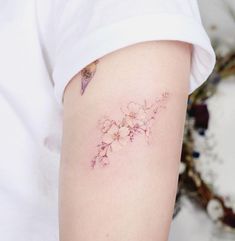 a close up of a person's arm with a flower tattoo on the left side