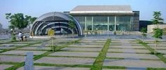 an artistic rendering of a building with grass in the foreground and people walking around