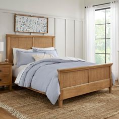 a bed sitting in a bedroom next to a wooden dresser and lamp on top of a rug