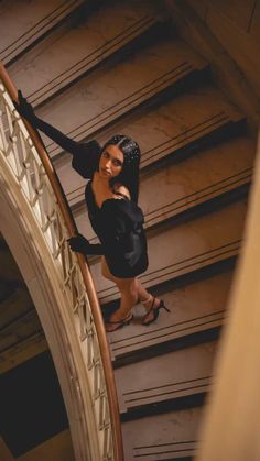 a woman is walking down the stairs in high heels and black dress, with her hands on her hips