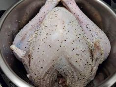 a whole chicken in a pot with some seasoning on it's head and legs