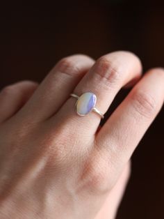 This dainty and extremely delicate ring features a beautiful Australian Lightning Ridge opal, set in a fine silver bezel with open back. The band is made with a sterling silver square wire. Size 6Handmade It's a perfect everyday ring - simple, yet full of character. Can be stacked and combined with other rings or worn by itself, for a more minimalist look. Delicate purples make each opal absolutely unique, with its own stunning colours and inclusions. The look of the gemstone changes in differen Silver Opal Stackable Rings As Gift, Delicate Silver Opal Ring In Sterling Silver, Minimalist Adjustable Opal Ring, Dainty Stackable Sterling Silver Opal Ring, Sterling Silver Opal Ring With Bezel Setting As Gift, Gift Opal Ring With Bezel Setting In Sterling Silver, Adjustable Minimalist Moonstone Ring In Sterling Silver, Minimalist Opal Birthstone Ring, Minimalist Adjustable Sterling Silver Moonstone Ring