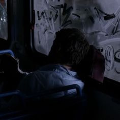 a man sitting in a bus looking at graffiti on the wall