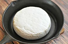 a piece of cheese sitting in a frying pan on top of a wooden table