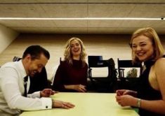 three people sitting at a table smiling for the camera while another person sits in front of them