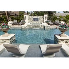 an outdoor swimming pool with lounge chairs and fire place in the center, surrounded by landscaping