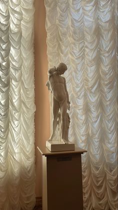 a statue is standing in front of curtains