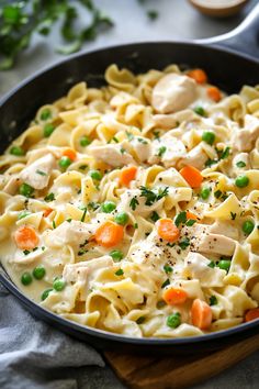 a skillet filled with chicken noodle and carrots