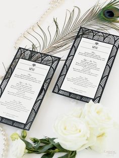 two black and white menu cards with peacock feathers on the table next to flowers, pearls and beads