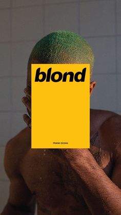 a man with green hair is holding up a yellow sign that says blond in front of his face