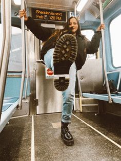 a woman is hanging upside down on the subway car with her feet in the air