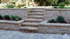 a stone wall with steps leading up to it and plants growing in the planters