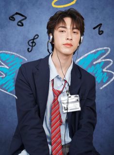 a young man wearing headphones sitting in front of a blue wall with music notes on it