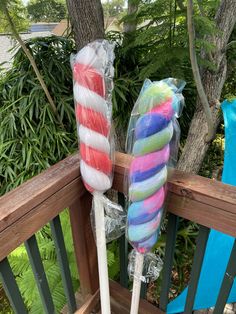 two lollipops wrapped in plastic sitting on top of a wooden deck next to a tree