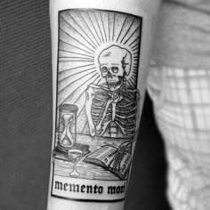 a person with a tattoo on their arm that reads mementoo man and has a skeleton reading a book