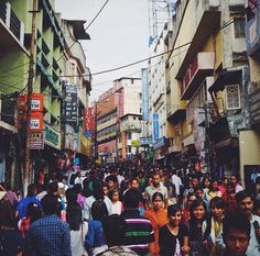 a crowd of people walking down a street next to tall buildings