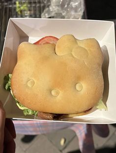 a hello kitty sandwich with lettuce and tomato in a white paper container on a table