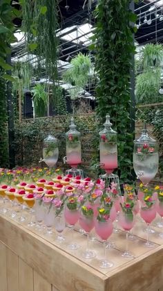 a table topped with lots of wine glasses filled with pink liquid and flowers in vases