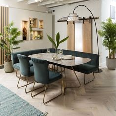 a dining room table with blue chairs and a plant in the corner next to it