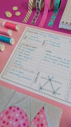 some crafting supplies are laying out on a pink table with scissors, tape and paper