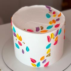 a white cake with multicolored confetti on it sitting on a plate