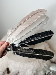 a person holding two feathers in their hand, one is white and the other is black