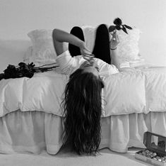 a black and white photo of a woman laying on a bed with her hair blowing in the wind