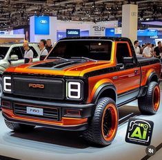 an orange and black truck on display at a car show