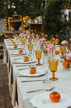 a long table is set with orange and pink flowers