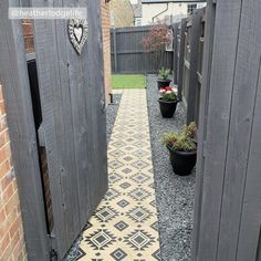 an outdoor walkway with potted plants between two wooden doors that lead to the back yard