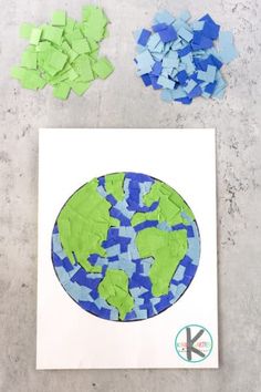 the earth is made out of blue and green pieces of paper with scissors next to it