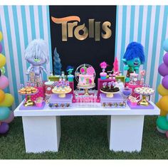 a table topped with lots of desserts and balloons in front of a sign that says trais