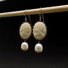 These gorgeous earrings start with off-white West German vintage glass profile cameos, placed these in gold plated lace settings. Suspended from these are plump freshwater pearls, with a great luster and minor incursions  (AAA) The earrings are 1.25 inches (3cms) in length including the quality 14kt gold-filled earwires. Any other questions feel free to contact me. To see more of my designs, including necklaces, bracelets and pearl jewelry, click on any of the links below: https://www.etsy.com/a Victorian Cameo Yellow Gold Earrings, Victorian Cameo Earrings For Formal Occasions, Classic Cameo Earrings, Gold Cameo Round Earrings, Cameo Drop Earrings For Formal Occasions, Classic Cameo Earrings Gift, Elegant Cabochon Pearl Drop Earrings, Gold Cameo Earrings For Wedding, Elegant Cameo Earrings As Gift