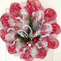 a red and white christmas wreath on a door