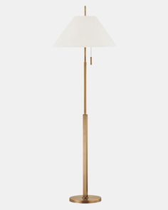 a gold floor lamp with a white shade on the base and a light bulb in the middle