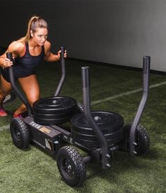 a woman is doing exercises on an exercise cart with two large black tires and one smaller black tire