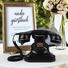 an old - fashioned phone sits on a table next to a framed sign that says, audio guestbook