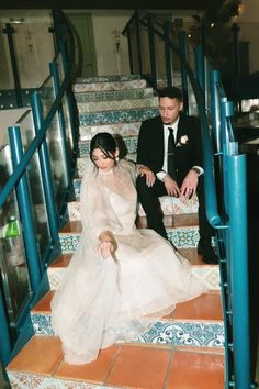 a bride and groom are sitting on the stairs