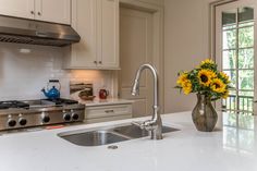 a vase with sunflowers in it sitting on a kitchen counter next to a sink