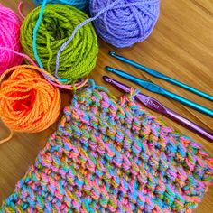 several balls of yarn sitting on top of a table next to crochet hooks