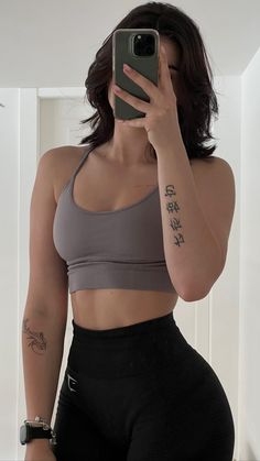 a woman taking a selfie with her cell phone in front of her face and wearing black leggings