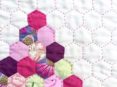 a close up of a patchwork quilt with hexagons and flowers on it