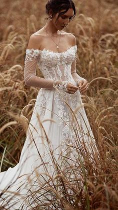 a woman in a white dress standing in tall grass