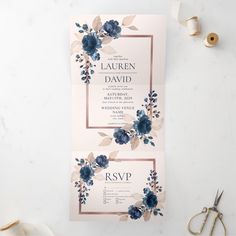 two wedding cards with blue flowers and greenery are on a table next to some scissors